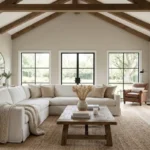 A cozy modern farmhouse living room with a white slipcovered sofa and wood beams