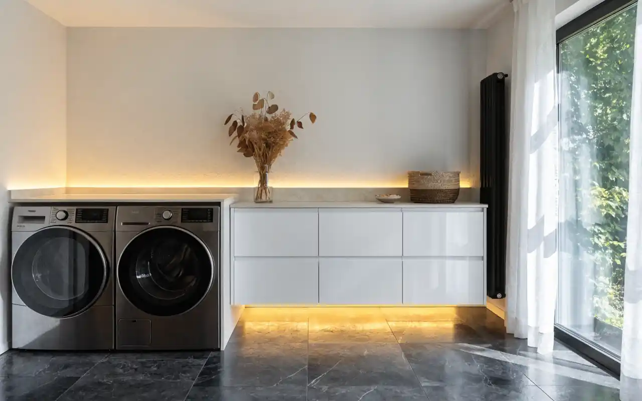 Modern floating white cabinets in a laundry room with under-cabinet lighting and a slate floor.