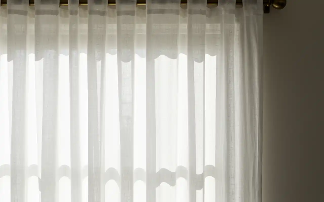 Sheer linen curtains blowing in the breeze of a small, bright sunroom.