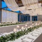 A stunning, high-end wedding reception with abundant greenery and warm candlelight on DIY tables.