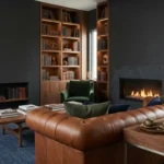 A luxurious man cave with charcoal walls, a leather Chesterfield sofa, and a custom walnut library.