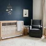 A luxurious boy nursery with navy walls, soft oak furniture, and a modern brass chandelier.