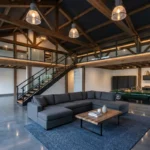 A luxurious pole barn man cave with a mezzanine loft, polished floors, and exposed timber trusses.