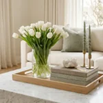 A luxurious spring coffee table styled with white tulips, brass accents, and designer books.