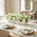 A luxurious spring tablescape with white tulips, gold cutlery, and linen linens on a marble table.