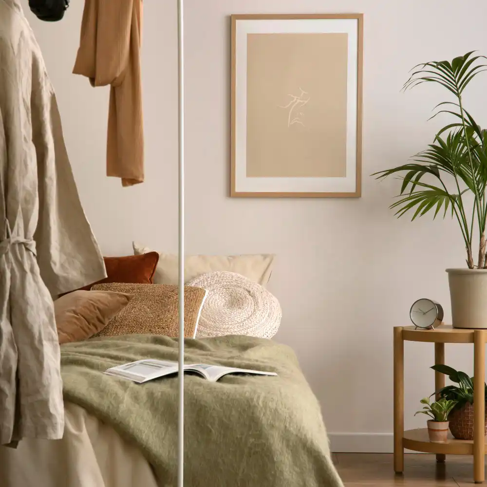 Hands measuring a headboard with a tape measure to size wall art two-thirds the width of the bed
