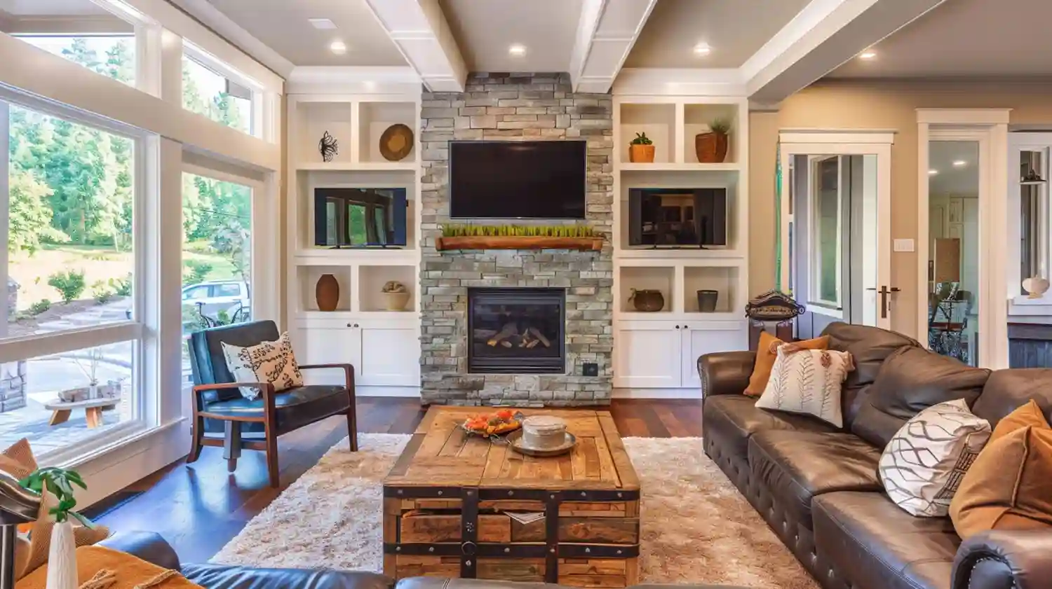 Wide living room with built-in shelves flanking a stone fireplace painted warm cream with natural oak floors and ceramic styling