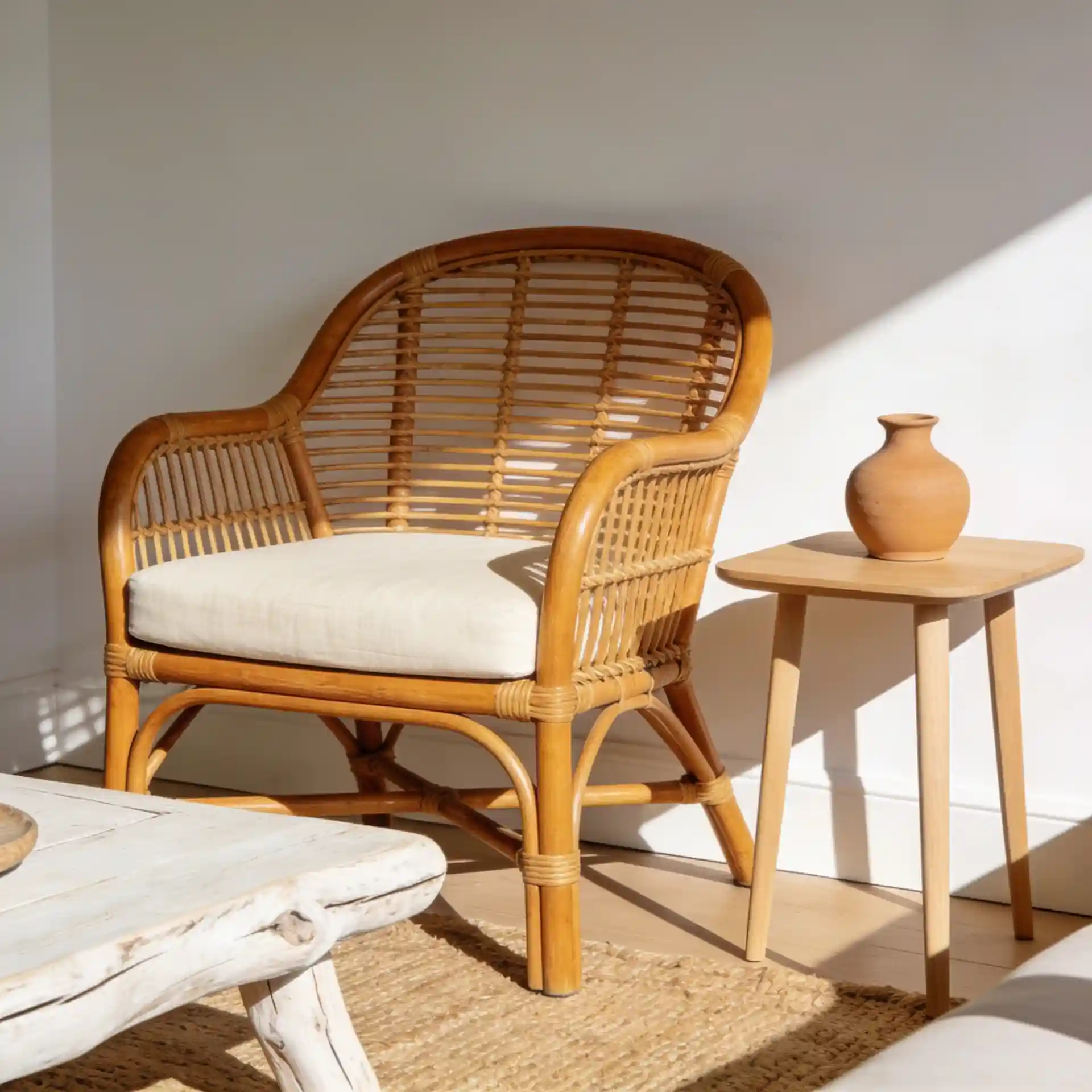 Coastal living room corner with honey rattan accent chair, light oak side table, and whitewashed driftwood coffee table