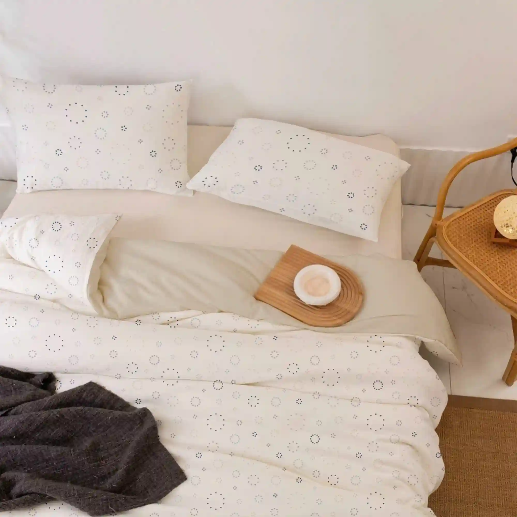 Cottagecore dorm bed with white floral cotton duvet, natural linen pillowcases, and a waffle-weave cream blanket