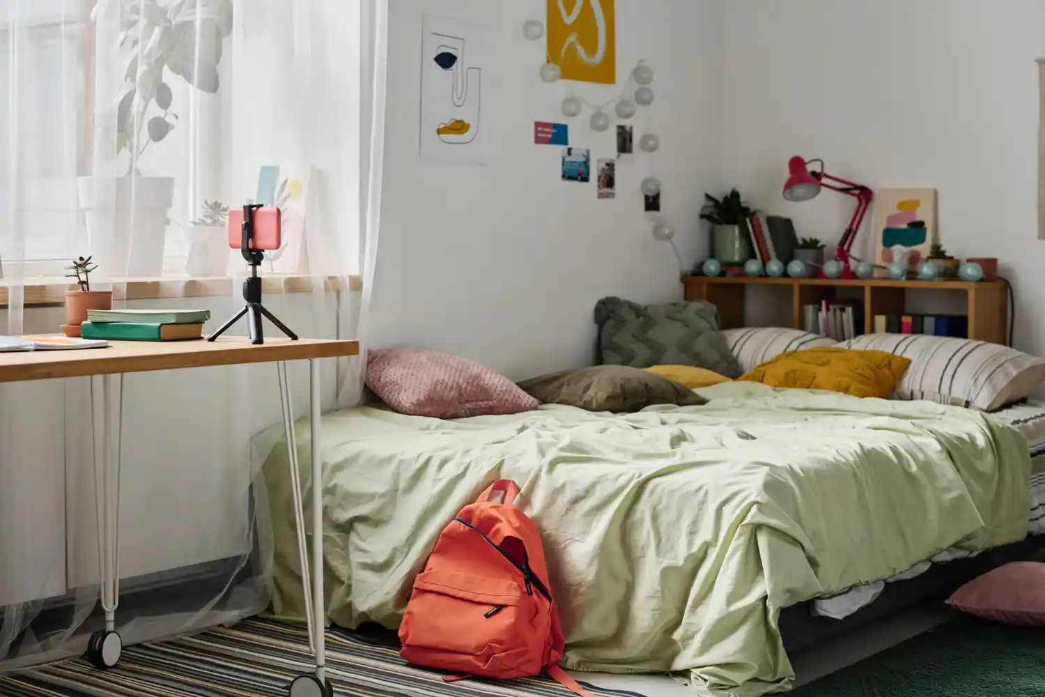 Cozy dorm room with a layered Twin XL bed in sage green and cream linen, decorative pillows, and a chunky knit throw