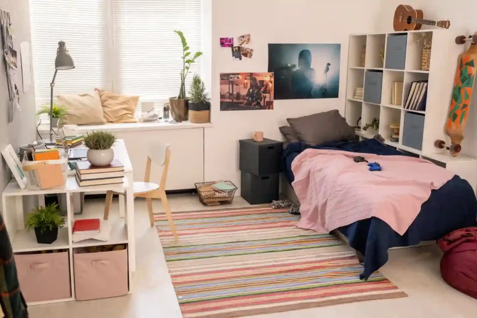 Bright college dorm room with lofted bed, warm lamp, jute rug, and personal gallery wall creating a cozy home-like space