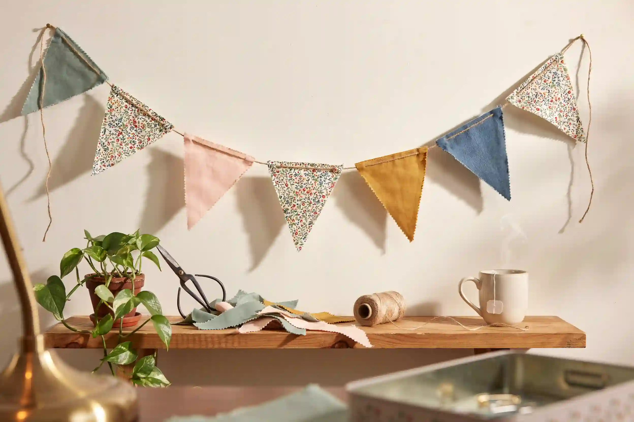 Fabric scrap bunting garland in muted spring prints draped across a styled wooden mantel