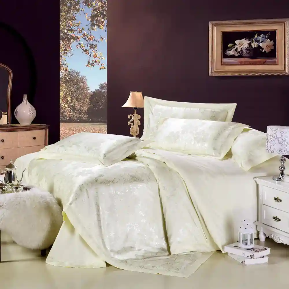 Deep layered bed with washed linen duvet, folded blanket, and stacked pillows in cream, oat, and soft clay