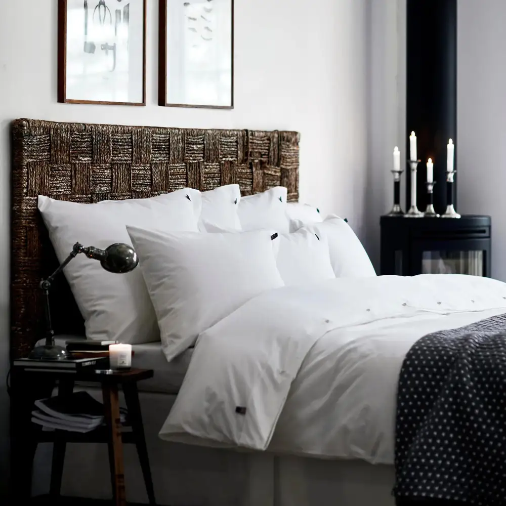 Hotel-style bed with crisp white sheets, lofty duvet, folded coverlet, and Euro shams