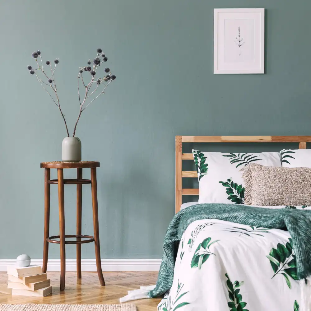 Bold teal accent wall behind walnut platform bed in a mid-century modern bedroom with cream linen