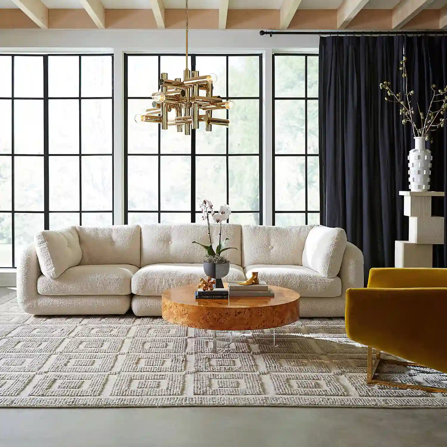 Large wool rug anchoring a low-profile velvet sofa and accent chairs in a modern living room