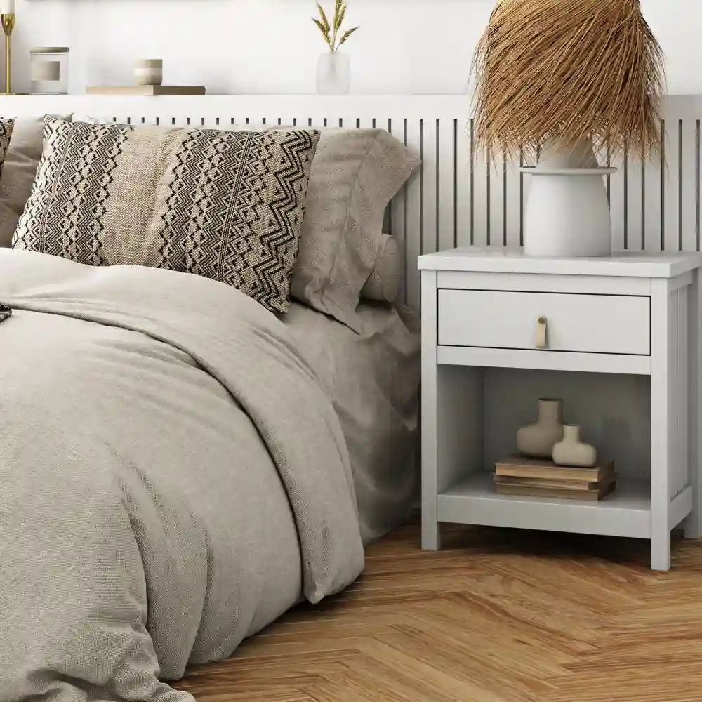 Warm rustic bedroom corner with raw wood accent wall, aged brass table lamp, and layered cream linen on bed