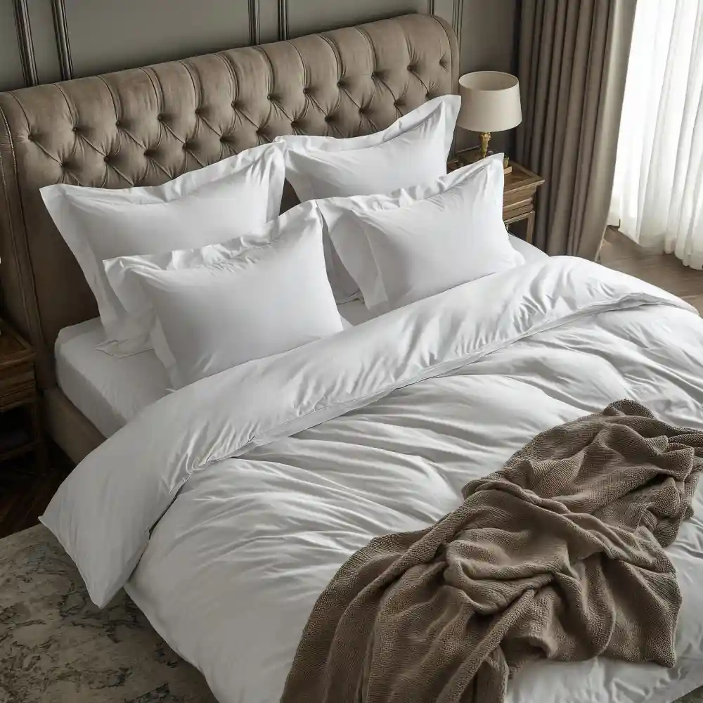 White bed layered with linen duvet, cotton sheets, knit throw, and textured euro shams