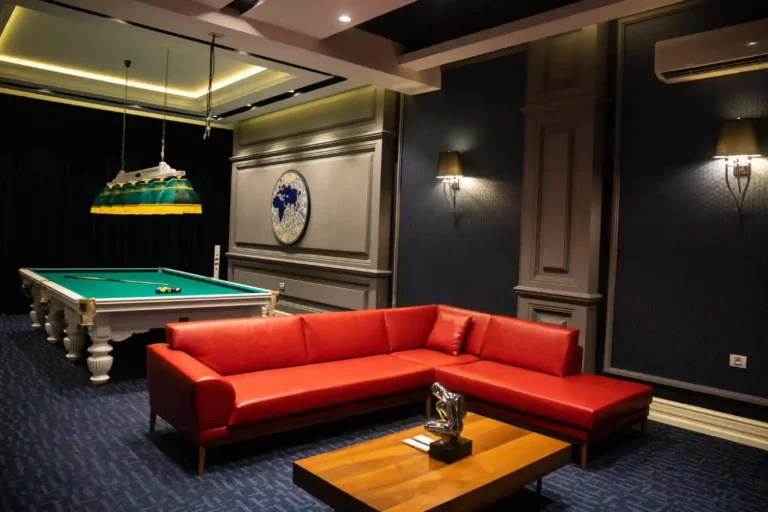 Budget man cave with charcoal wall, thrifted cognac chair, used media console, warm lamps, rug, and framed sports art