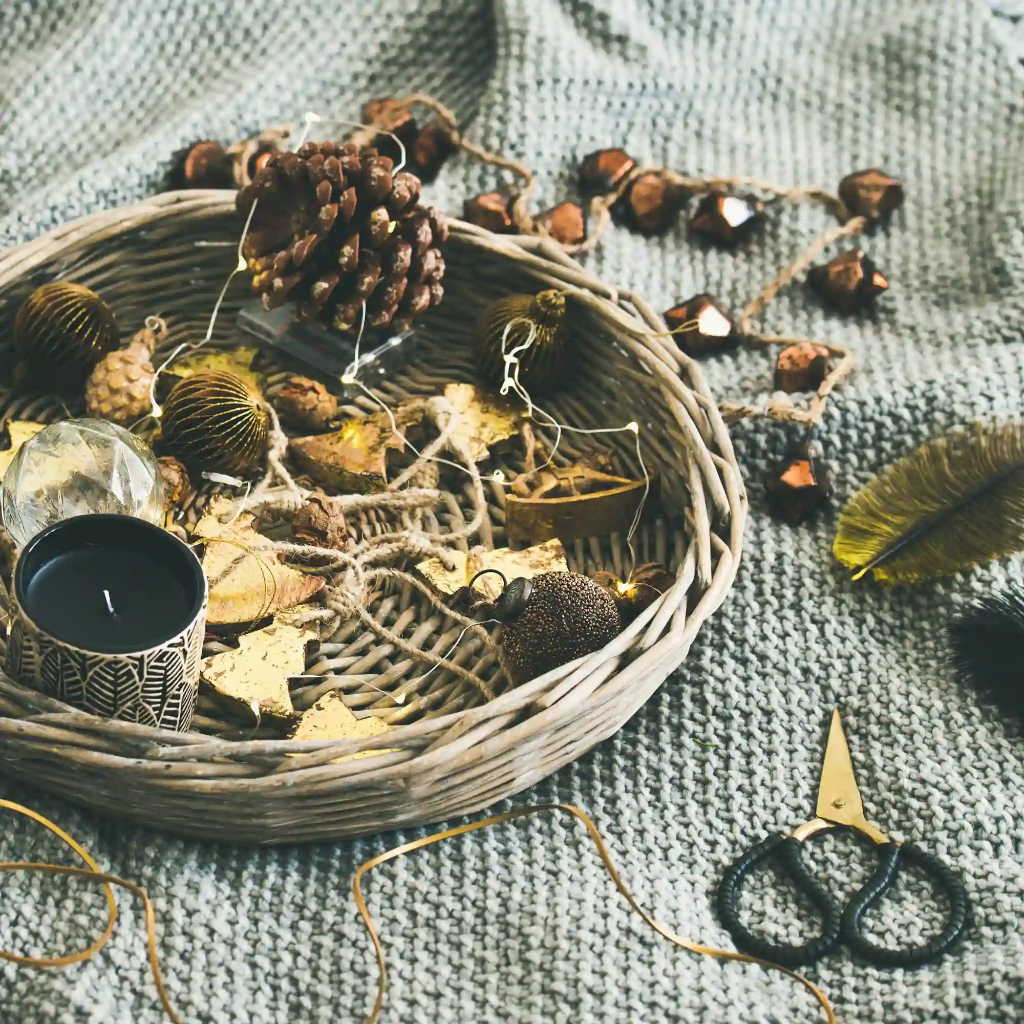Woven basket holding foraged oak branches and dried hydrangea beside a linen runner and wood tray