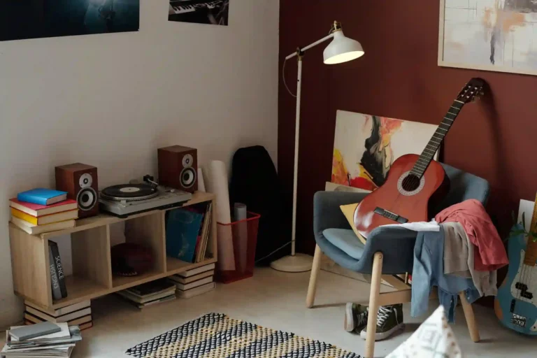 Finished home music man cave with charcoal walls, guitar gallery wall, cognac armchair, and warm floor lamp