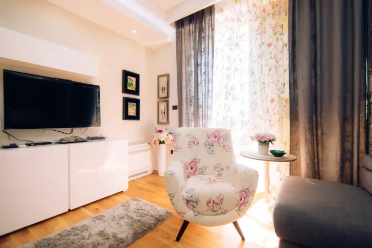Bright open-plan one-bedroom apartment with a warm greige sofa, large mirror, and layered lamp lighting