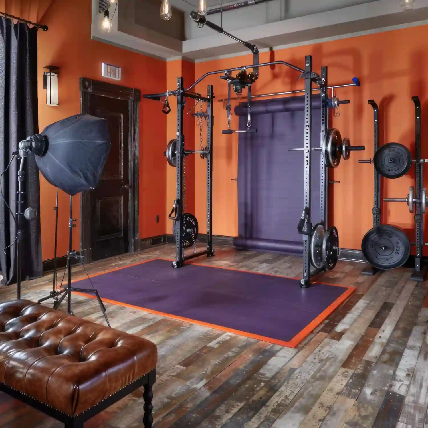 Close-up of black interlocking rubber gym tiles under a squat rack in a garage gym
