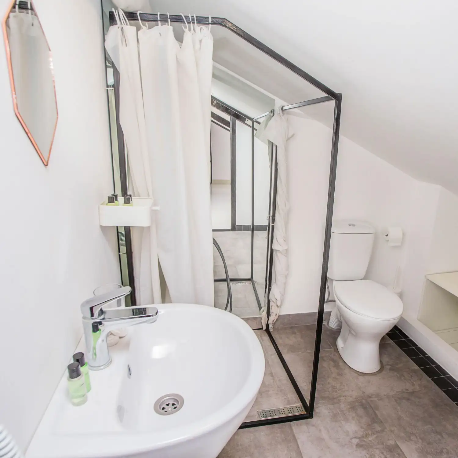 Side by side bathroom showing a fabric shower curtain on one tub and a clear glass shower door on another