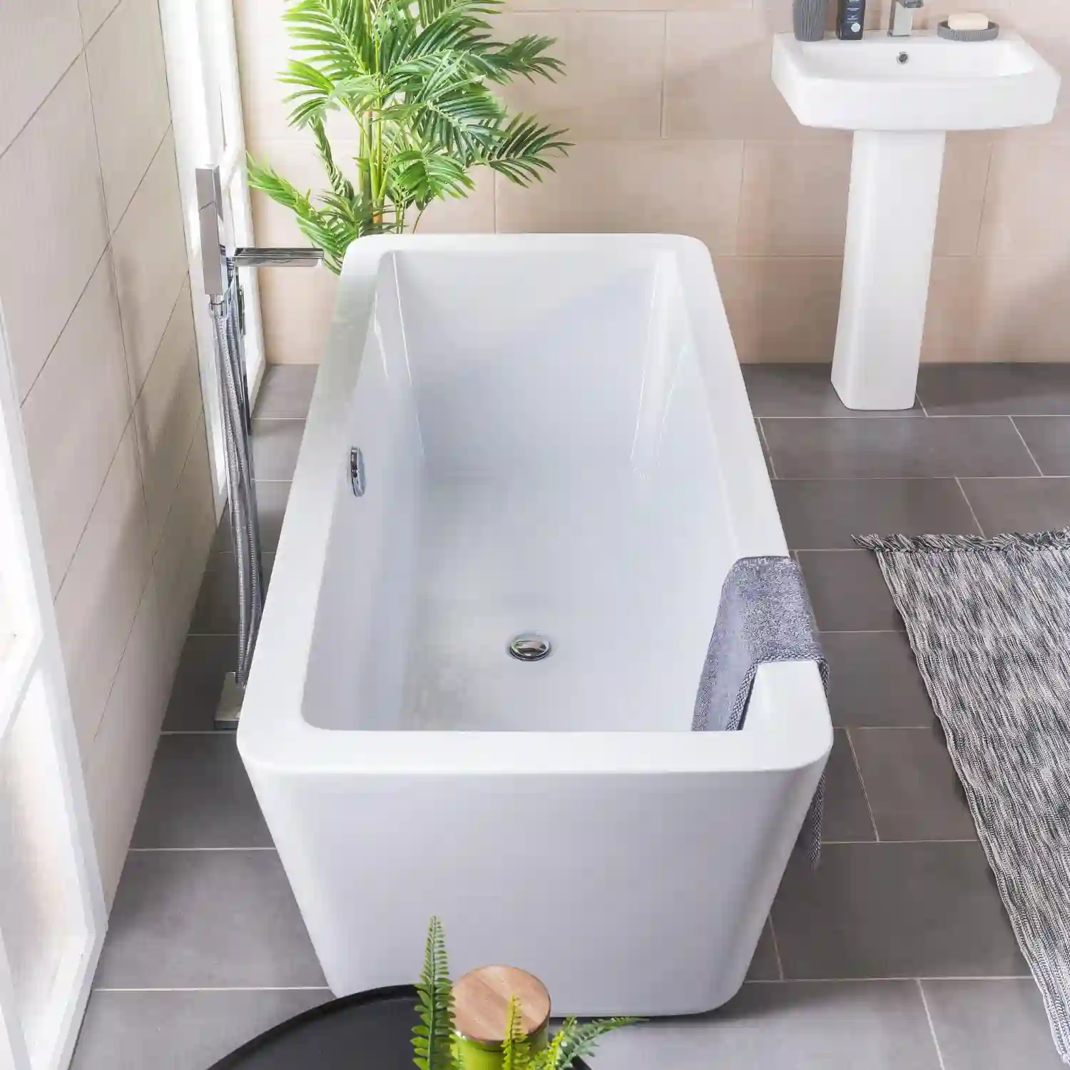 Cast iron clawfoot tub beside a pedestal sink in a black-and-white tiled vintage bathroom