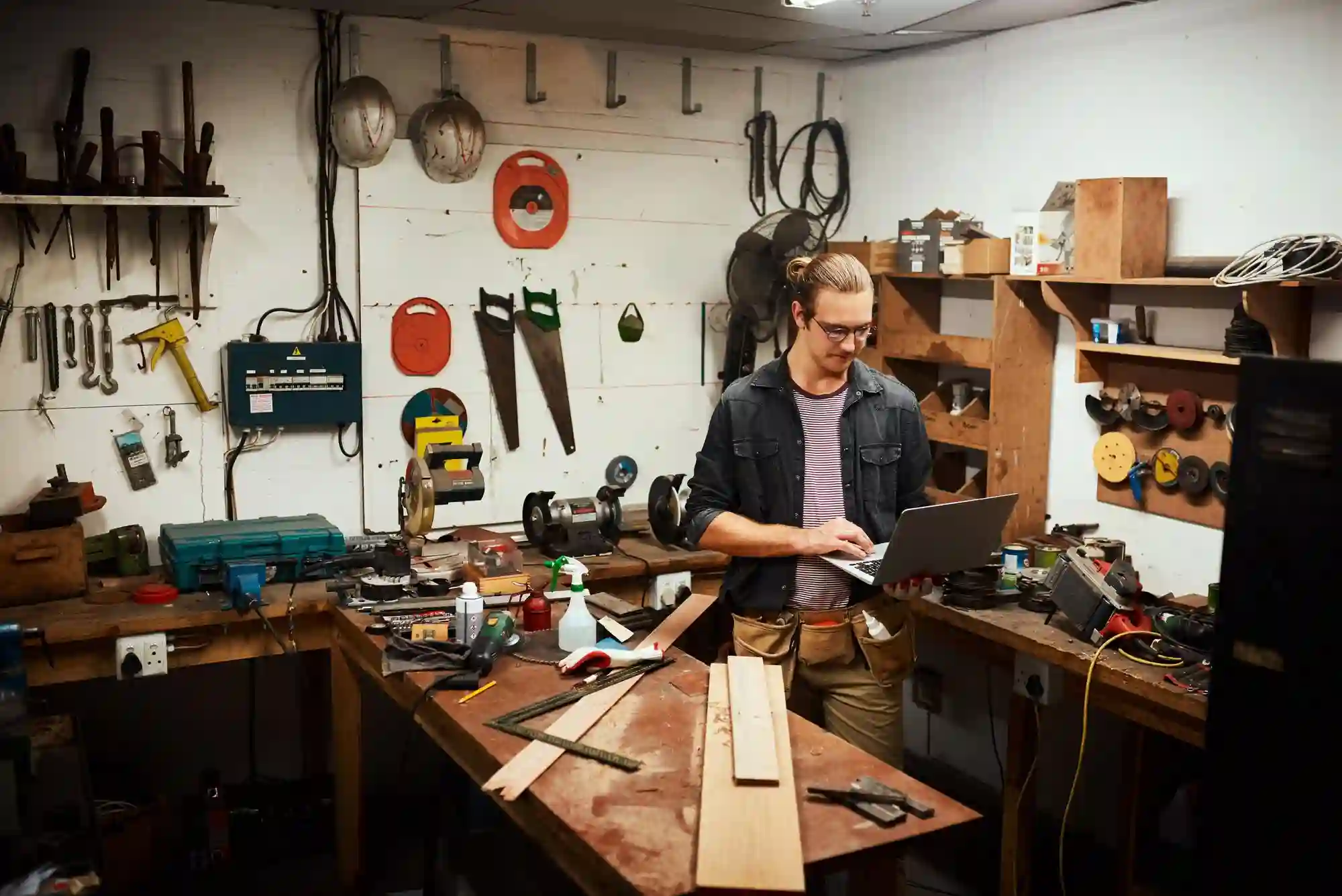 Collage of a workbench zone, pegboard wall, layered shop lighting, and a lounge corner in a workshop man cave